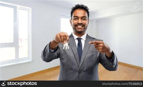 real estate business and people concept - indian man realtor with keys over empty new apartment room background. indian man realtor with home keys at new apartment