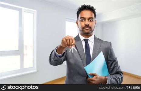 real estate business and people concept - indian man realtor with keys and folder over empty new apartment room background. indian man realtor with home keys and folder