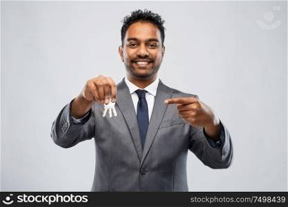 real estate business and people concept - indian man realtor with keys over grey background. indian man realtor with keys and folder