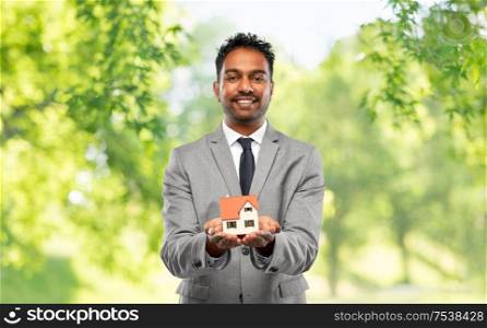 real estate business and people concept - man realtor with house model over green natural background. man realtor with house model and folder