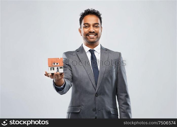real estate business and people concept - man realtor with house model over grey background. man realtor with house model and folder