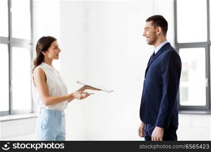 real estate business, sale and people concept - female realtor with clipboard showing contract document to customers at new office room. realtor showing contract document to customer