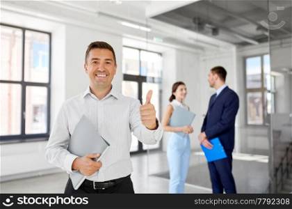 real estate business, sale and people concept - happy smiling realtor or businessman with folder showing thumbs up and customers at new office room. realtor with folder showing thumbs up at office