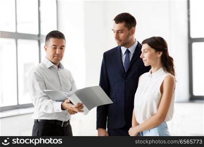 real estate business, sale and people concept - happy smiling realtor with folder showing documents to customers at new office room. realtor with folder showing documents to customers