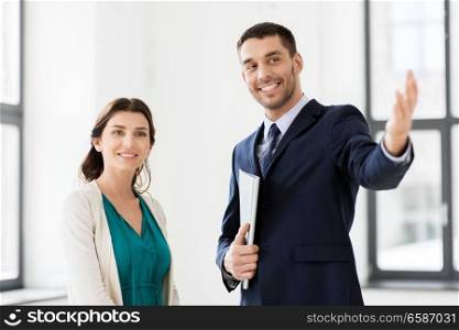 real estate business, sale and people concept - happy smiling realtor with folder showing new office room to female customer. realtor showing new office room to female customer