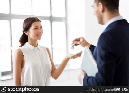 real estate business, sale and people concept - male realtor giving key to female customer or new office owner. realtor giving key to customer at new office. realtor giving key to customer at new office