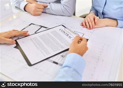 real estate business, sale and people concept - male realtor with blueprint showing contract document to customers at office. realtor showing contract document to customers
