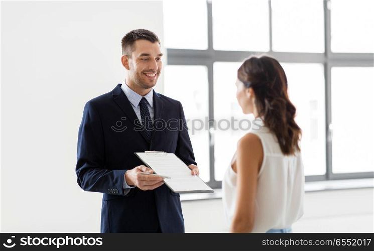 real estate business, sale and people concept - male realtor with clipboard showing contract document to customers at new office room. realtor showing contract document to customer. realtor showing contract document to customer