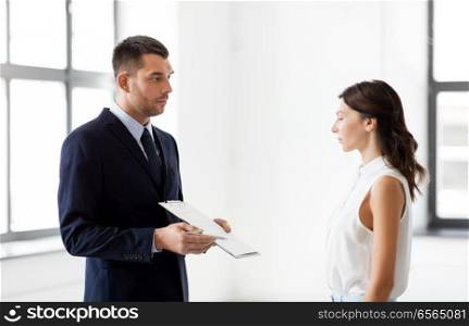 real estate business, sale and people concept - male realtor with clipboard showing contract document to customers at new office room. realtor showing contract document to customer