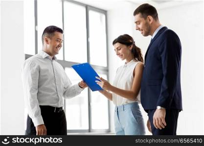 real estate business, sale and people concept - male realtor with clipboard and pen showing contract document to customers at new office room. realtor showing contract document to customers