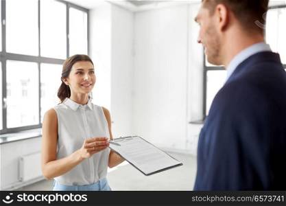 real estate business, sale and people concept - male realtor with clipboard showing contract document to customer at new office room. realtor showing contract document to customer