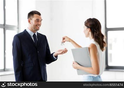 real estate business, sale and people concept - realtor giving key to customer or new office owner. realtor giving key to customer at new office. realtor giving key to customer at new office