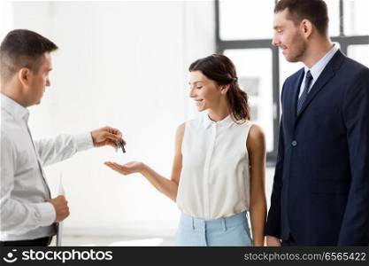 real estate business, sale and people concept - realtor giving key to customers or new office owner. realtor giving key to customers at new office