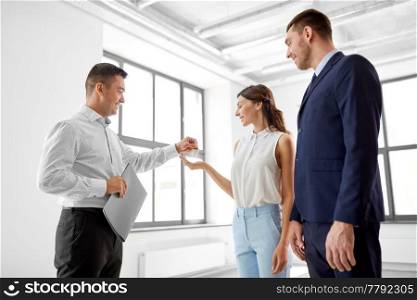 real estate business, sale and people concept - realtor giving key to customers or new office owners. realtor giving key to customers at new office