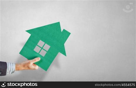 Real estate concept. Hand of business person holding house card