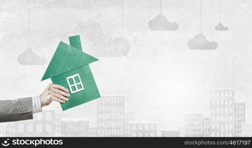 Real estate concept. Hand of business person holding house card