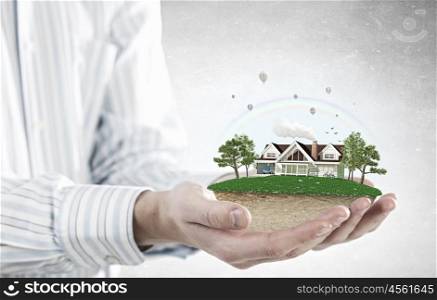 Real estate concept. Human hands holding model of dream house