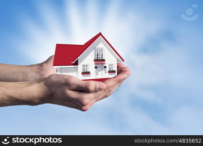 Real estate concept. Human hands holding model of dream house