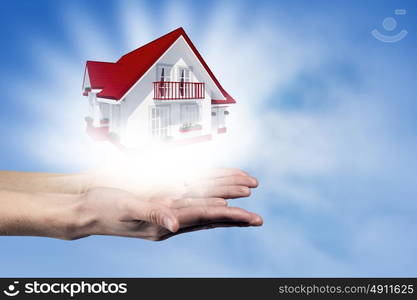 Real estate concept. Human hands holding model of dream house