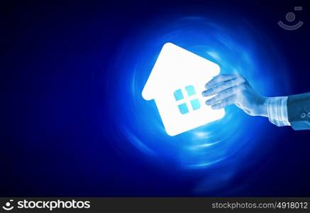 Real estate concept. Human hands holding model of house on blue background