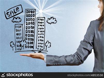 Real estate concept. Rear view of businesswoman holding sketch of building in palm