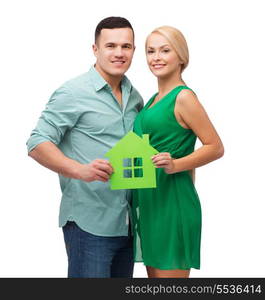 real estate, family and couple concept - smiling couple holding green paper house