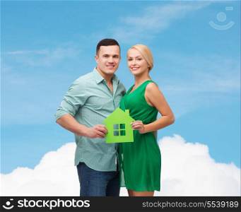 real estate, family and couple concept - smiling couple holding green paper house