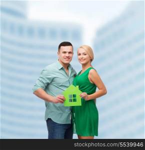 real estate, family and couple concept - smiling couple holding green paper house