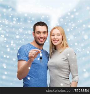 real estate, family, people and couple concept - smiling couple holding keys over snowy city center background
