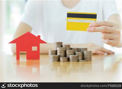 Real estate investment by credit card. House and coins on table.