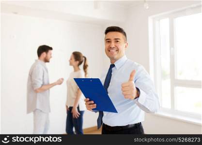 real estate, mortgage and people concept - happy smiling realtor with clipboard showing thumbs up and couple at new home. realtor with clipboard showing thumbs up