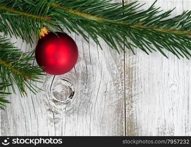 Real Grand Fir tree branch with single red ornament on rustic white wooden boards. Christmas season concept.