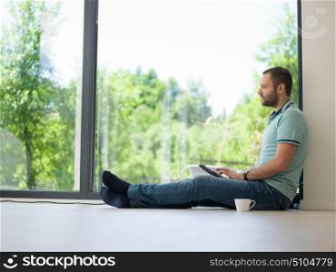 Real man Using tablet on the floor At Home Drinking Coffee Enjoying Relaxing