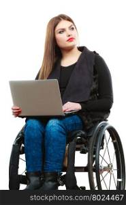 Real people, disability and handicap concept. Teen girl unrecognizable person sitting on wheelchair using laptop computer networking, studio shot on white