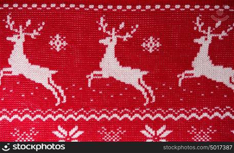 Real red knitted background with white Christmas deers and snowflakes