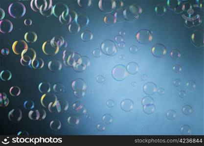 Real soap bubbles floating mid-air over blue background.