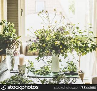 Real summer bouquet made from field wild flowers on a table in a modern living room by the window. Summer still life. Cozy home scene