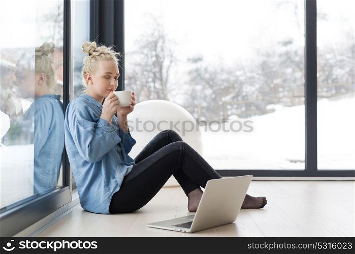 Real Woman Using laptop on the floor Drinking Coffee Enjoying Relaxing at cold winter day