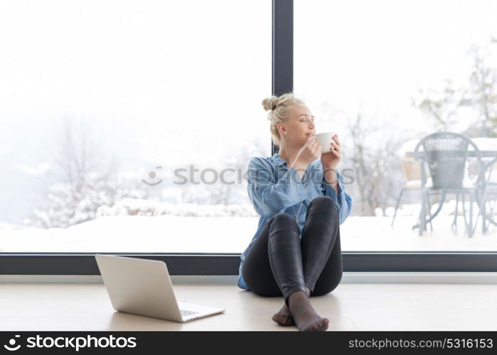 Real Woman Using laptop on the floor Drinking Coffee Enjoying Relaxing at cold winter day