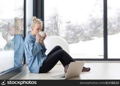 Real Woman Using laptop on the floor Drinking Coffee Enjoying Relaxing at cold winter day