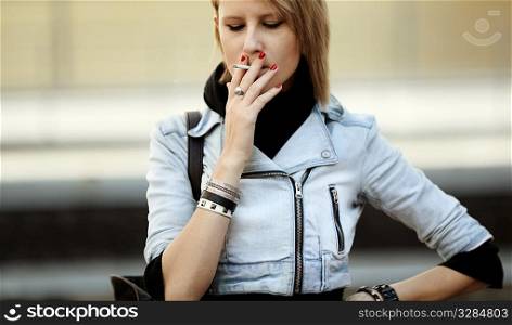 real young woman smokes on the street, natural light, selective focus