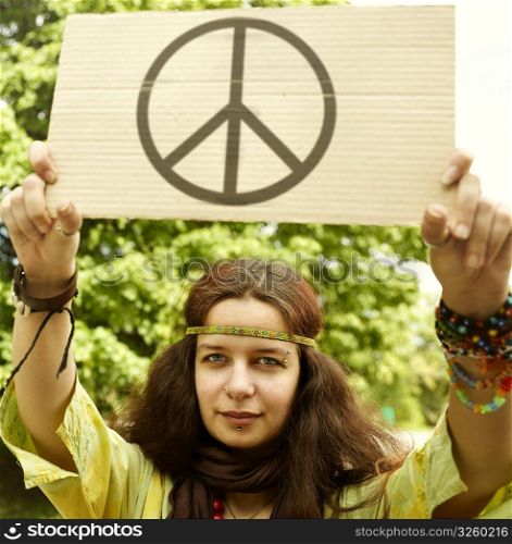 Real young woman with cardboard with well-known peice symbol,selective focus on eye