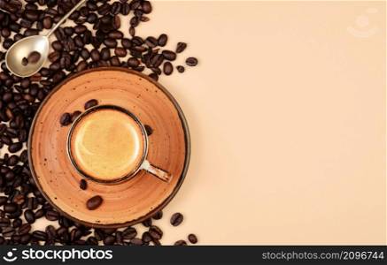 Realistic top view of black cup of espresso view from above, pastel peach color background. Cup with coffee crema and coffee beans.Template with copy space for your text.