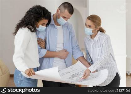 realtor couple with medical masks looking house plans