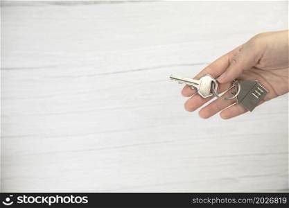 realtor female hand holding new door key to new house on white background top view with copy space, buying new home concept space for text. realtor female hand holding new door key to new house on white background top view with copy space, buying new home concept