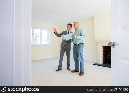 Realtor With Digital Tablet Showing Senior Man Looking To Downsize Around Retirement Home
