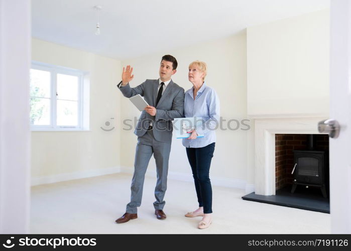 Realtor With Digital Tablet Showing Senior Woman Looking To Downsize Around Retirement Home