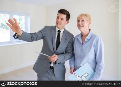 Realtor With Digital Tablet Showing Senior Woman Looking To Downsize Around Retirement Home