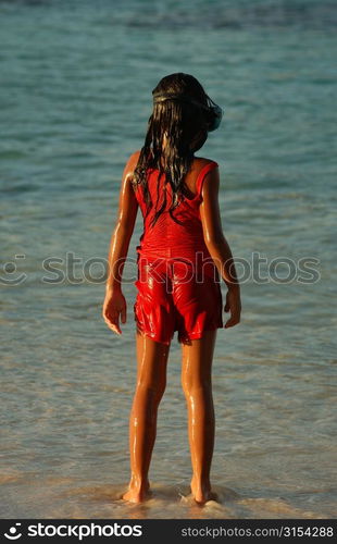 Rear of a young girl (8-9) standing on a beach, Moorea, Tahiti, French Polynesia, South Pacific