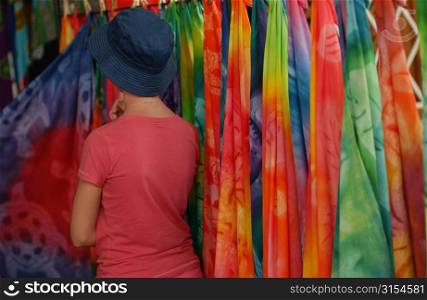 Rear of a young woman looking at the bright colored fabrics at the straw market, Papeete, Tahiti